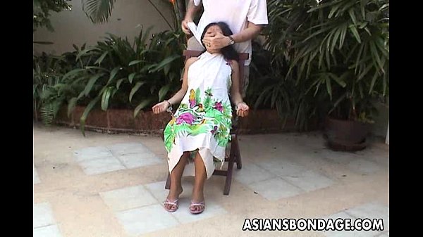 Asian teen tied up and hand cuffed on a chair