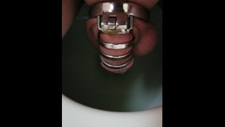 Guy sitting down to pee in a chastity cage!